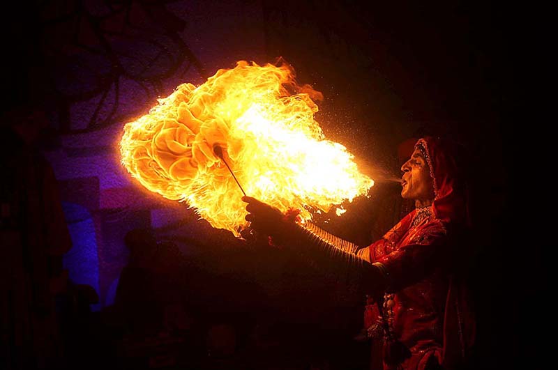 A woman performing art of blowing fire from her mouth during Folk Festival ‘Lok Mela’ 2022 at Lok Virsa