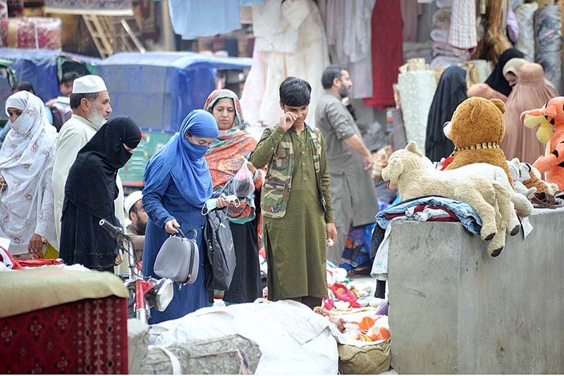Women customers selecting and purchasing second hand bags from a roadside vendor at Kohati area
