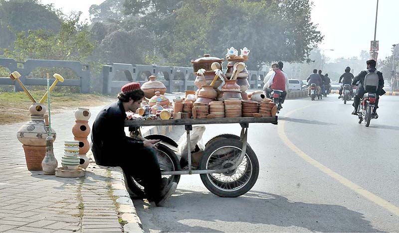 A vendor selling clay pots while sitting at roadside