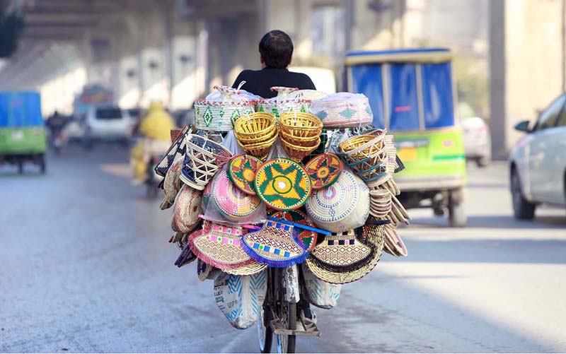 A street vendor on the way paddling his bicycle loaded with different kinds of stuff on Murree Road.