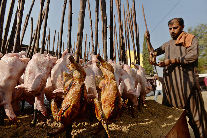 A vendor is roasting Traditional Balochi Sajji at a stall during ten days “Folk Festival Lok Mela” at Lok Virsa