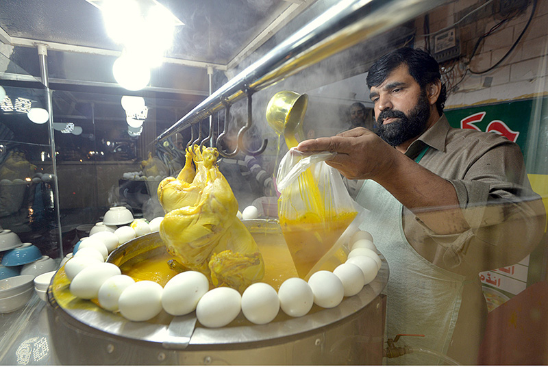 A vendor selling chicken soup (Yakhni) at his roadside setup during winter season.