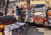 A worker displaying quilts at his workplace on per increased demand as the mercury drops rapidly in the city