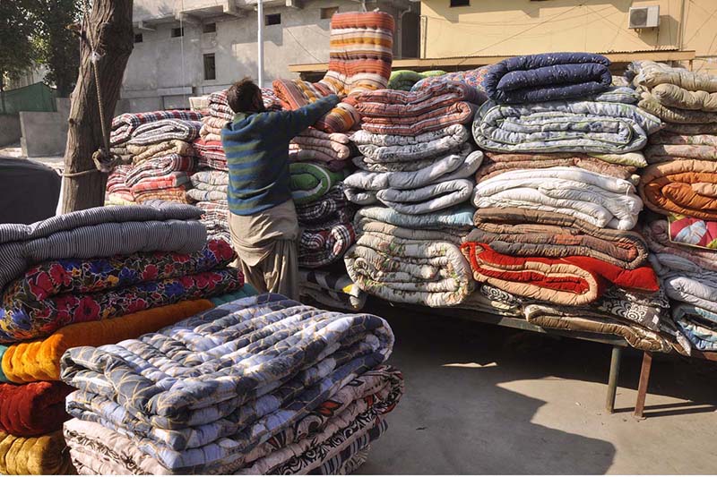 A worker displaying quilts at his workplace on per increased demand as the mercury drops rapidly in the city