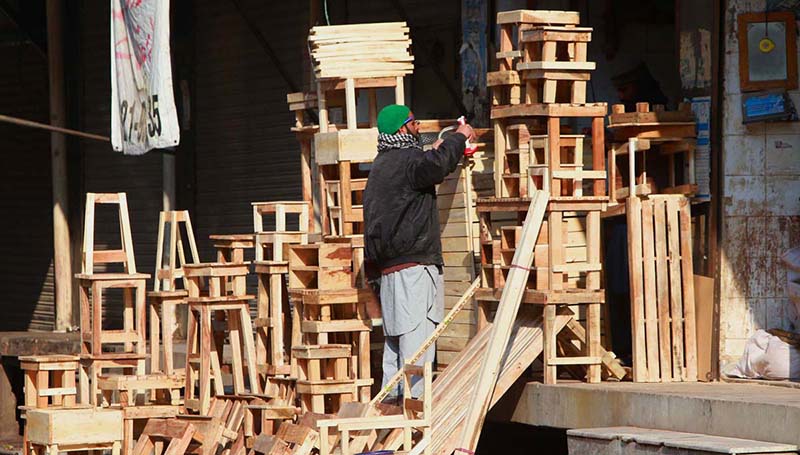 Carpenter preparing wooden stools at his work place at Bani Chowk.