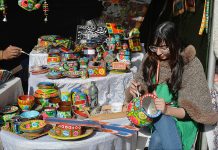 An artist is painting crafts with traditional truck art during ten days “Folk Festival Lok Mela” at Lok Virsa