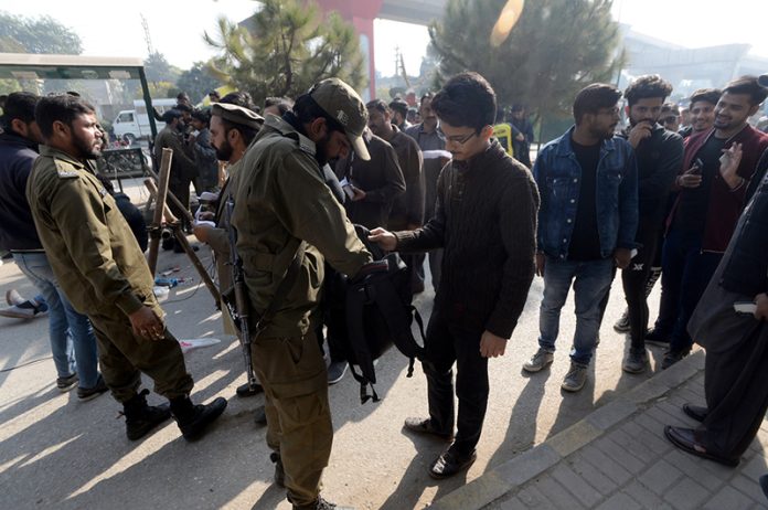 Police persons searching bag during the first day of test match between Pakistan and England at Murree Road.