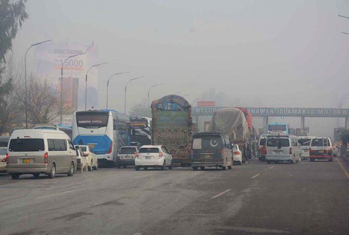 Large number of vehicles standing in queue at Motorway Toll Plaza which is closed due to heavy fog.