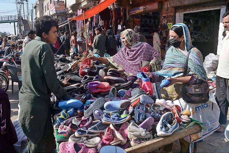 People purchasing old shoes from a vendor at Bara Bazar