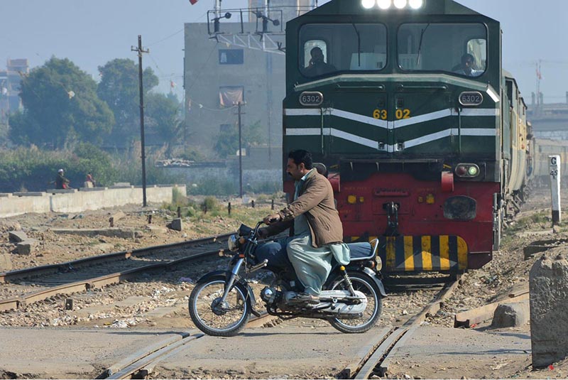 Motorcyclist crossing rail track while train is approaching