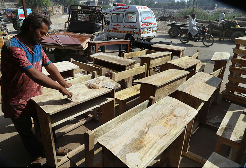 A worker polishing school benches at Makki Shah Area