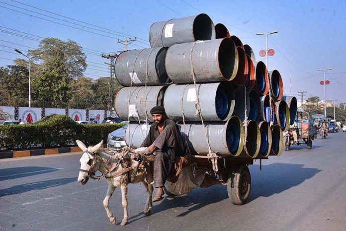 A donkey cart holder loaded with empty drums going towards his destination