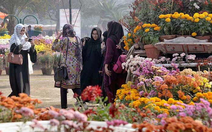Women capturing moment with cell phone while visiting at Flower Show in Jillani Park