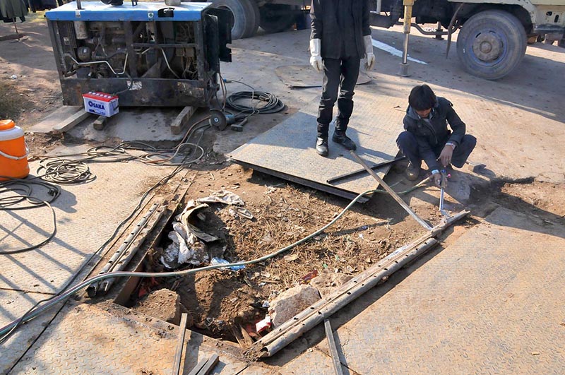 Workers repairing pedestrian bridge at Zia Masjid on Islamabad Expressway