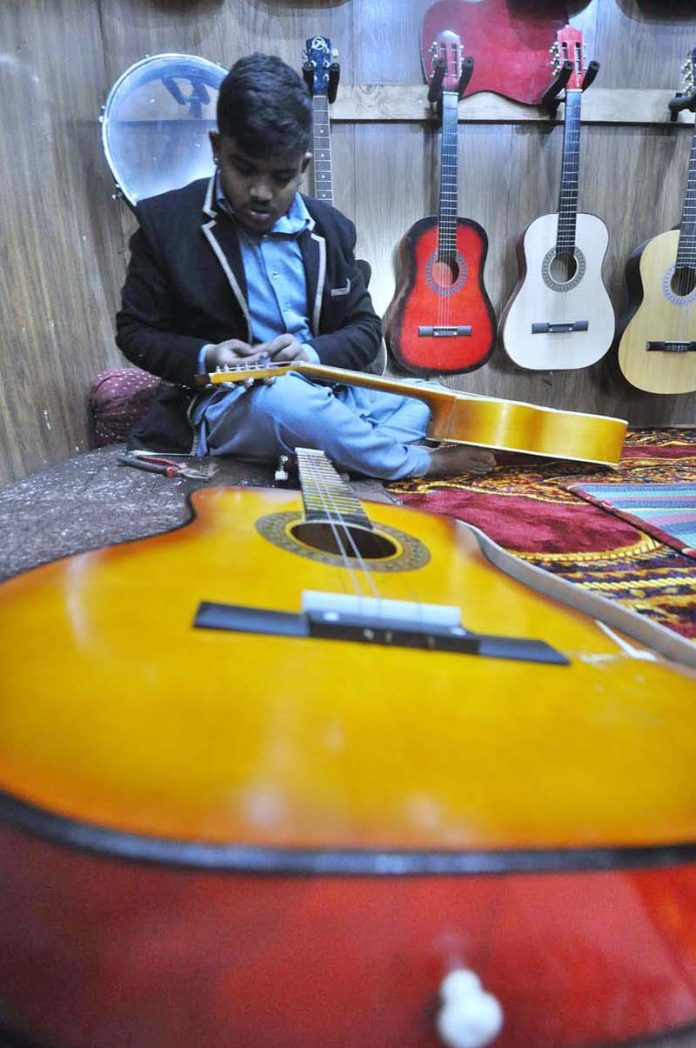 A skilled worker making musical instrument (guitar) at his workplace
