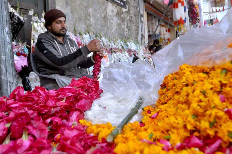 A vendor preparing flower garlands at his shop to attract customers