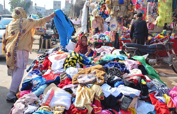 Women busy in selecting & purchasing second hands warm clothes from vendor at Station Road