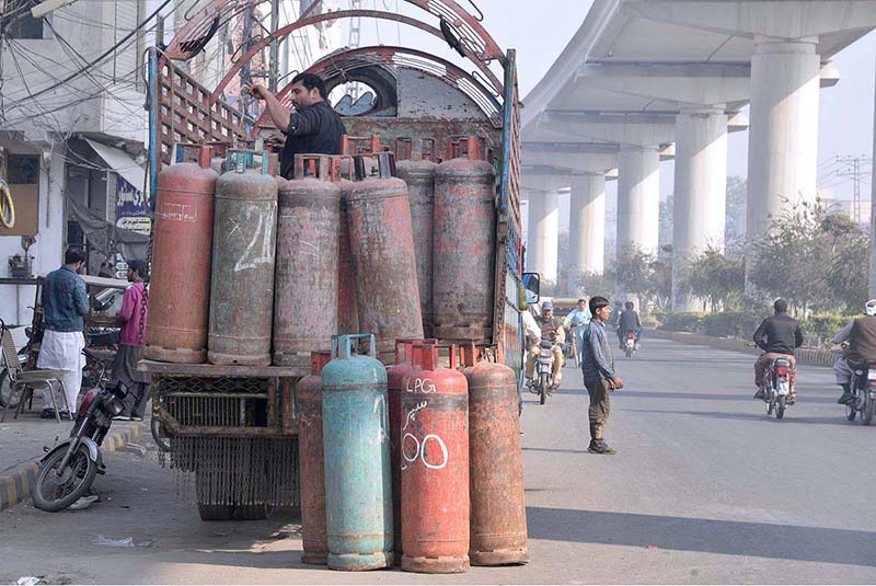 Labourer loading LPG cylinders on a delivery truck