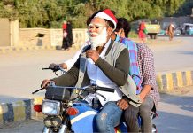 A motorcyclist on the way wearing Santa Claus mask in connection with upcoming Christmas