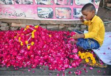 A youngster busy in preparing flower garlands at his shop to attract the customers