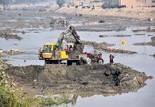 Labourers loading sand on tractor trolley with the help of machine at Rice Canal