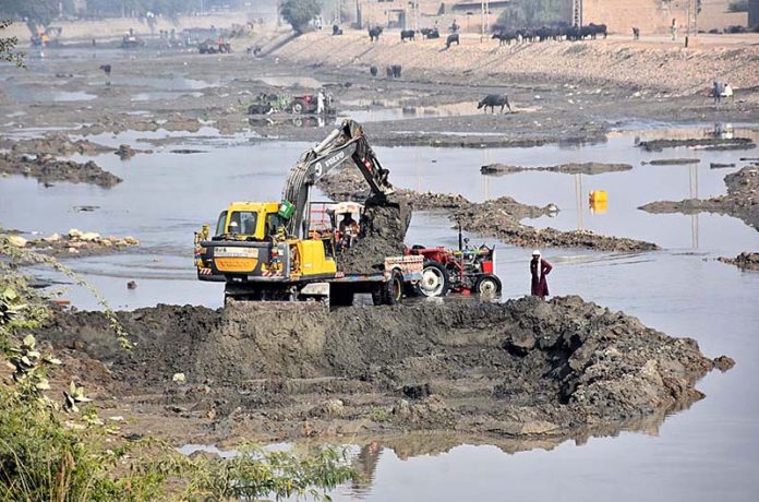 Labourers loading sand on tractor trolley with the help of machine at Rice Canal