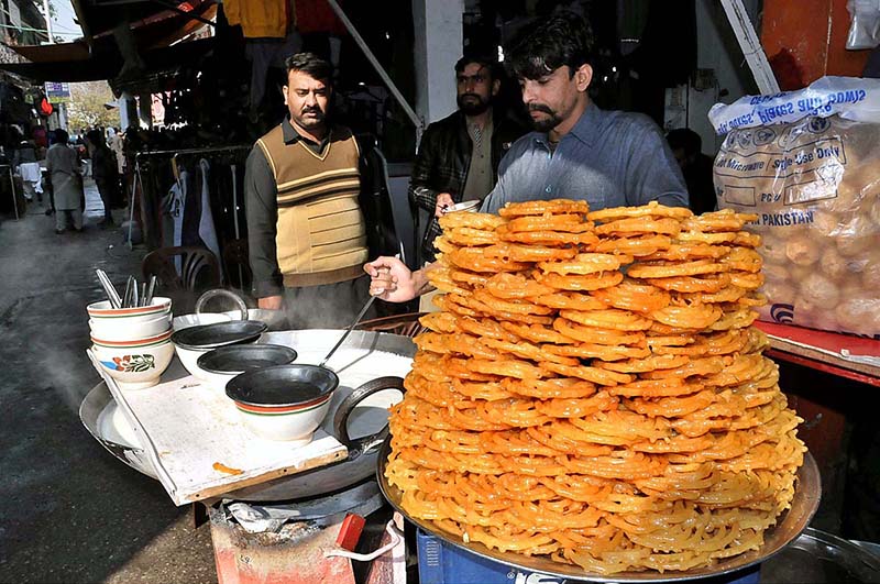 A vendor is preparing samosas for customers at his shop