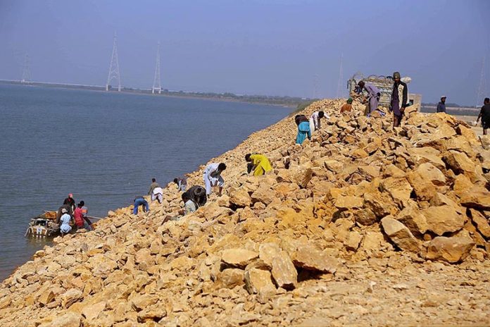 Labourers strengthening embankment after recent flooding due to heavy rain at Indus River near Kotri Barrage