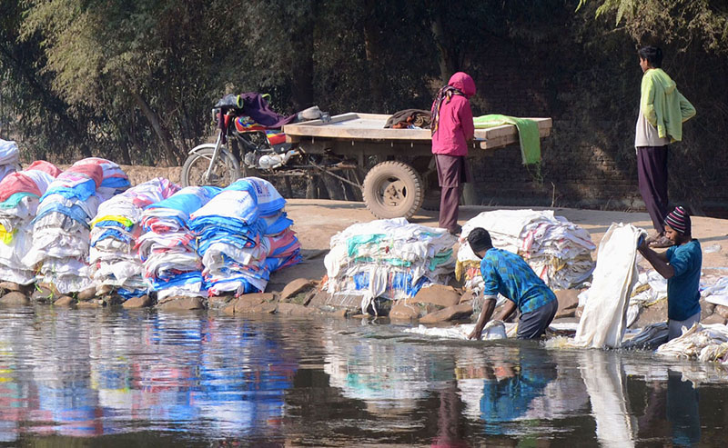 Labourers washing empty plastic bags on side of the Canal