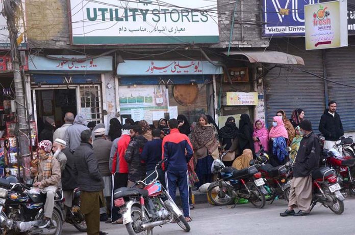 Large number of people in a queue to get groceries outside Utility Store.