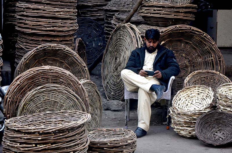 A vendor waiting for customers at his handmade traditional wooden basket at shop.