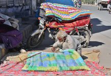An old man stitching quilt at roadside