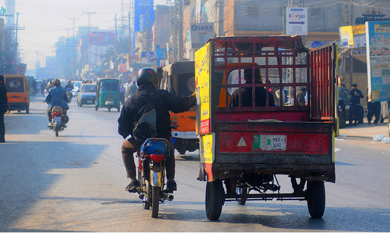 An out of order motorcyclist holding a loader rickshaw to reach his destination