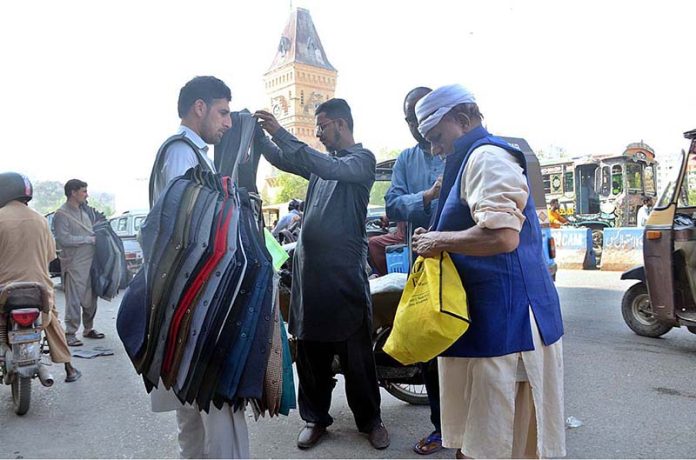 People are selecting and purchasing warm coat displayed by vendor on his road side setup at Saddar Area