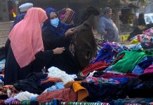 Ladies selecting and purchasing warm clothes from a roadside vendor