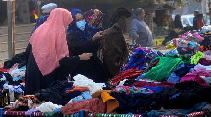 Ladies selecting and purchasing warm clothes from a roadside vendor