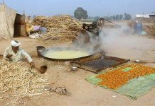 Labourer busy in boiling sugarcane juice for the preparation of traditional sweet item (Gurr) at his workplace