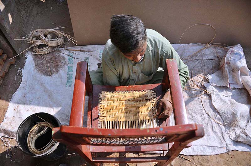 Worker busy in knitting a chair at his workplace