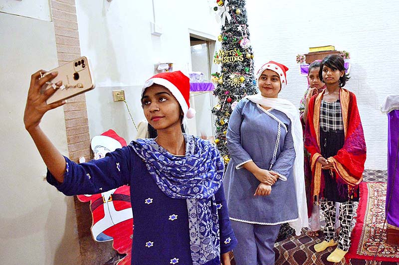 Christian girls taking selfie with decorated Christmas tree at local church in connection with upcoming Christmas