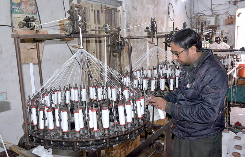 A factory worker working on yarn knitting machine at Local Factory