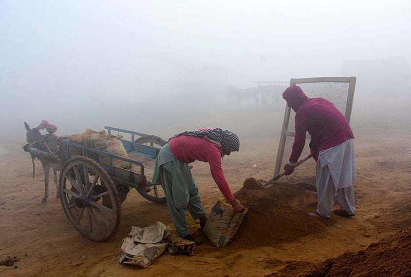 Labourers busy in their work during thick fog that engulfs the whole city in morning time