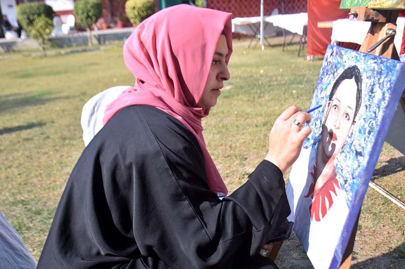 A girl giving final touch to her painting during family cultural festival "Jungle main mangal" organized by department of information and culture