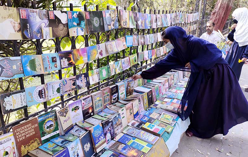 A Girl selecting the book displayed by a vendor at Jinnah Bagh.