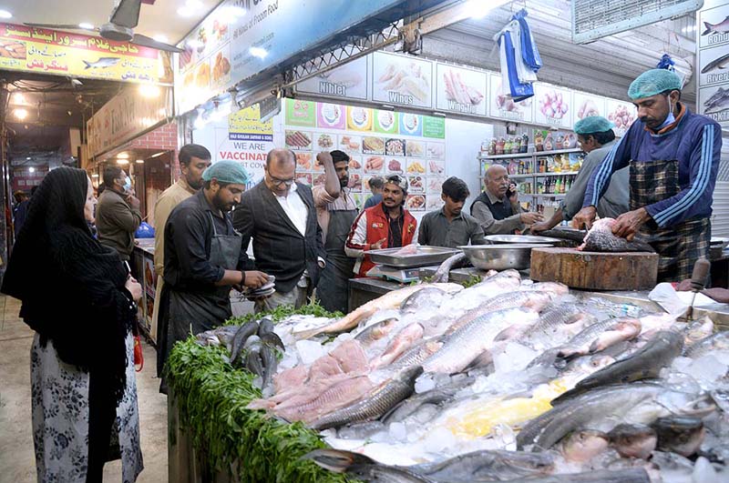 People purchasing fish from vendor in fish market.