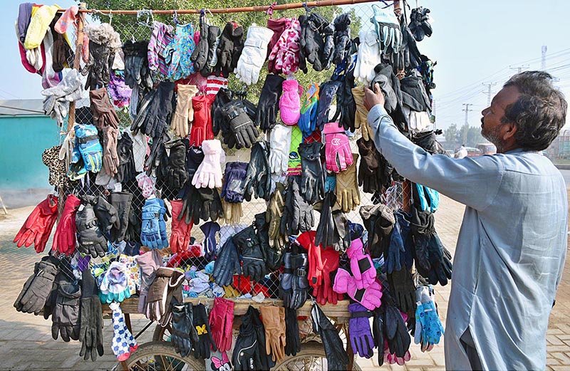 A person selecting and purchasing second hand gloves from a vendor at Latifabad