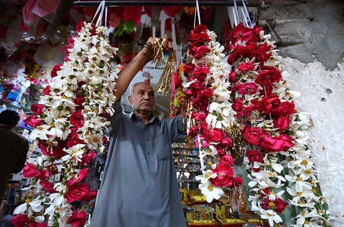 A vendor making flower garlands for customers at Fawara Chowk