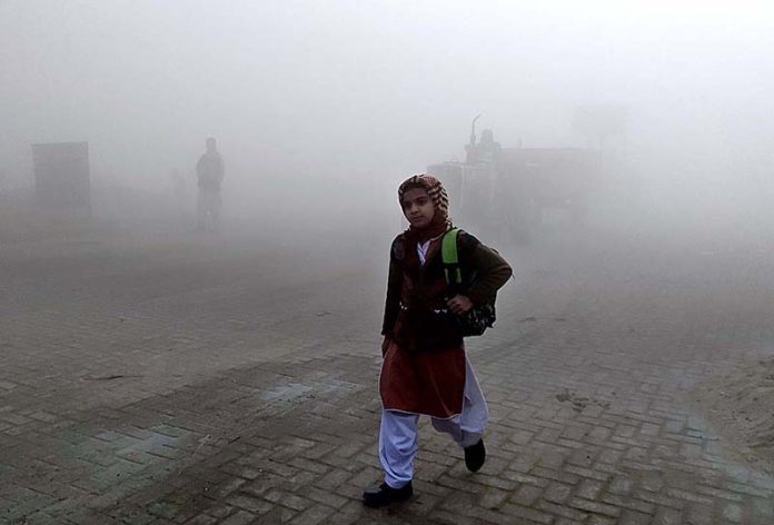 A student is going to school in the morning time during fog that engulfs the whole city