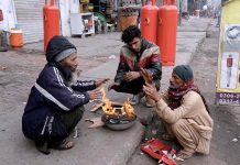 People are getting themselves warm with wood fire during winter season at Old Anarkali.