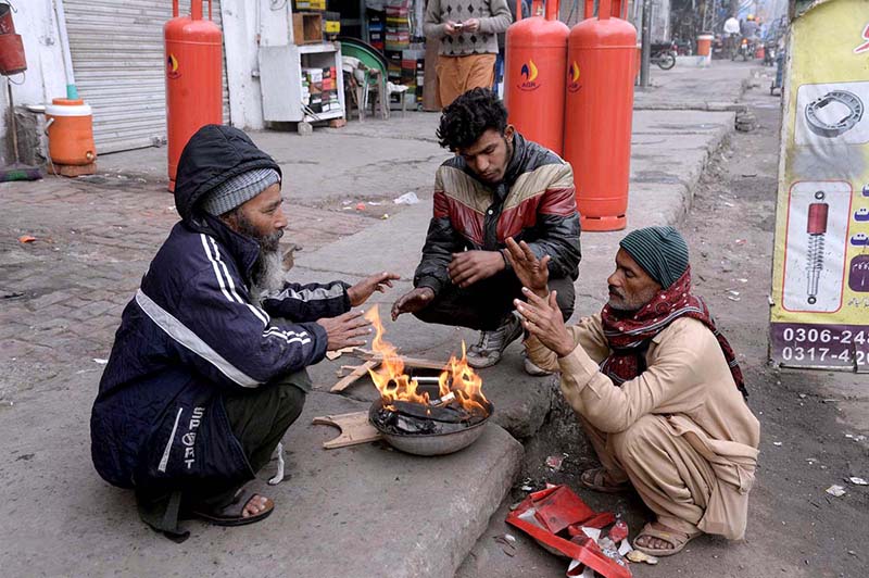 People are getting themselves warm with wood fire during winter season at Old Anarkali.