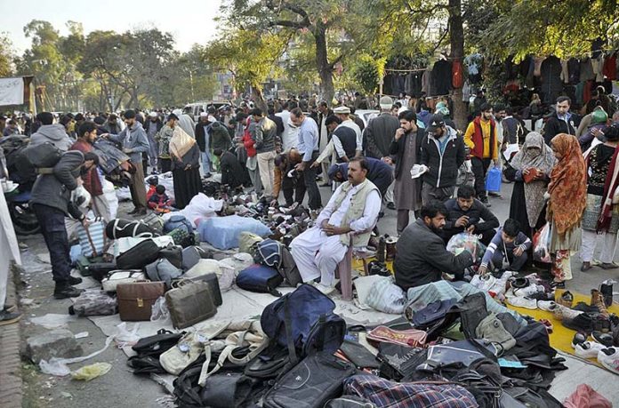 People selecting and purchasing secondhand shoes, bags and warm clothes from vendors at Abbapra Market